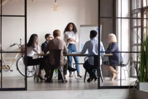 A woman presenting to a group of colleagues in a modern office conference room, with a bicycle and whiteboard in the background. | Firemní akce | A tak se stalo eventová agentura Olomouc